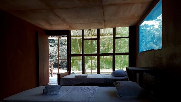 A room with two beds, a large window, and a view of trees and mountains. - My Amazon Lodge (Iquitos)