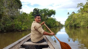 A person in a boat on a calm river surrounded by dense greenery. - My Amazon Lodge (Iquitos)