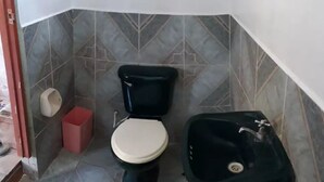 A small bathroom with a toilet, a sink, and a red trash bin. - My Amazon Lodge (Iquitos)