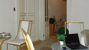 A room with a door, a chair, a table with a tray of items, a laptop, and a potted plant. - Hotel Velvet 1928 (Cairo)