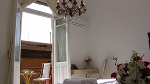A bedroom with a bed, a chair, a table, and a vase of flowers. - Hotel Velvet 1928 (Cairo)