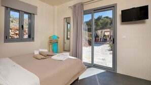 Un dormitorio con cama, televisor y puerta corrediza a un espacio exterior.