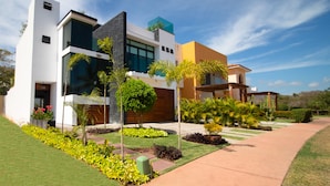 A modern two-story house with a garage, a well-maintained lawn, and a variety of plants. - Brisas 5 (La Cruz de Huanacaxtle)