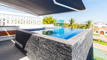 Alberca al aire libre, sombrillas en la alberca y camastros