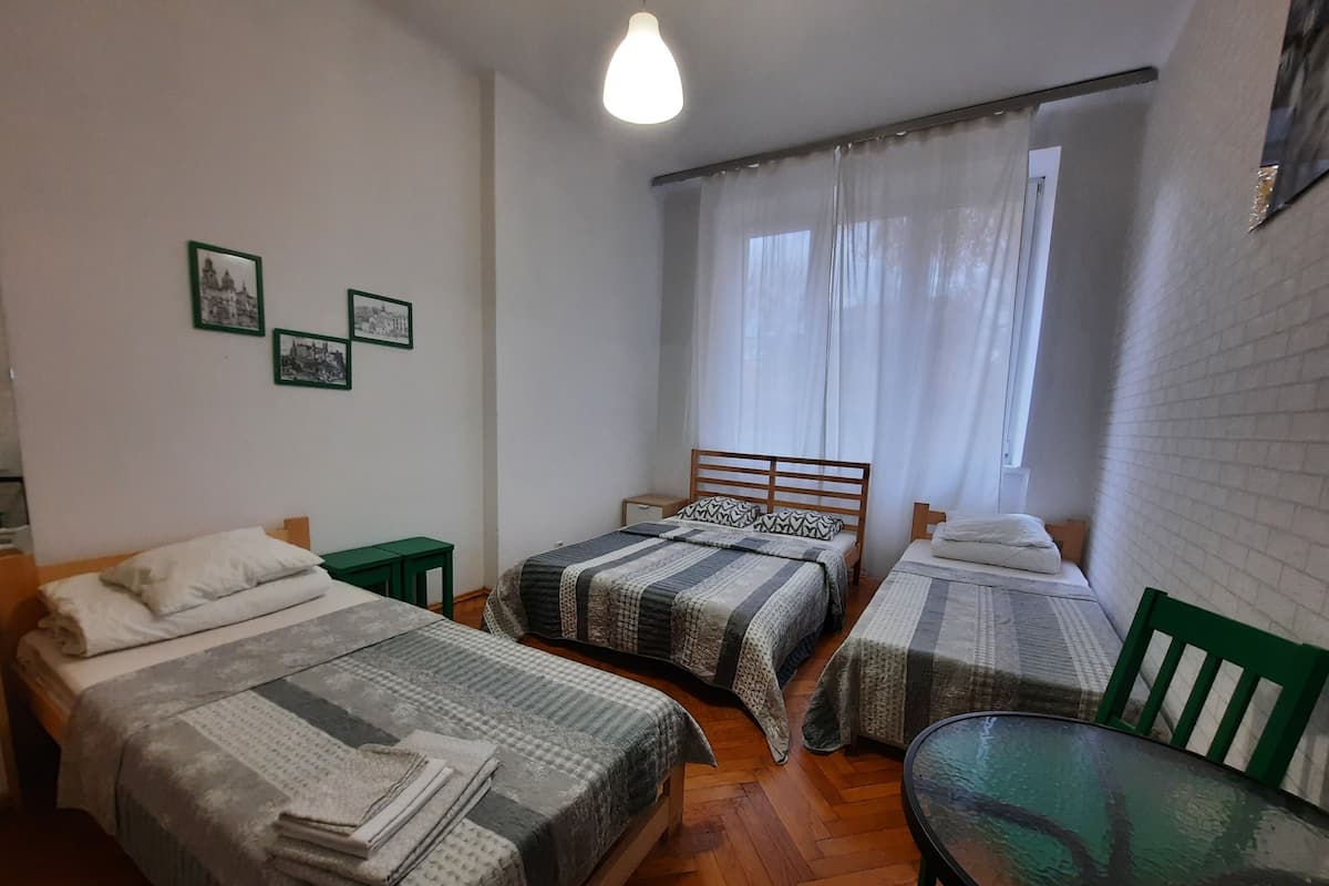A room with two beds, a table, and a window with curtains.