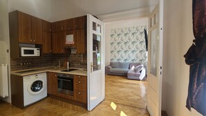 Una cucina compatta con mobili in legno, un forno a microonde, una lavatrice e un lavello.