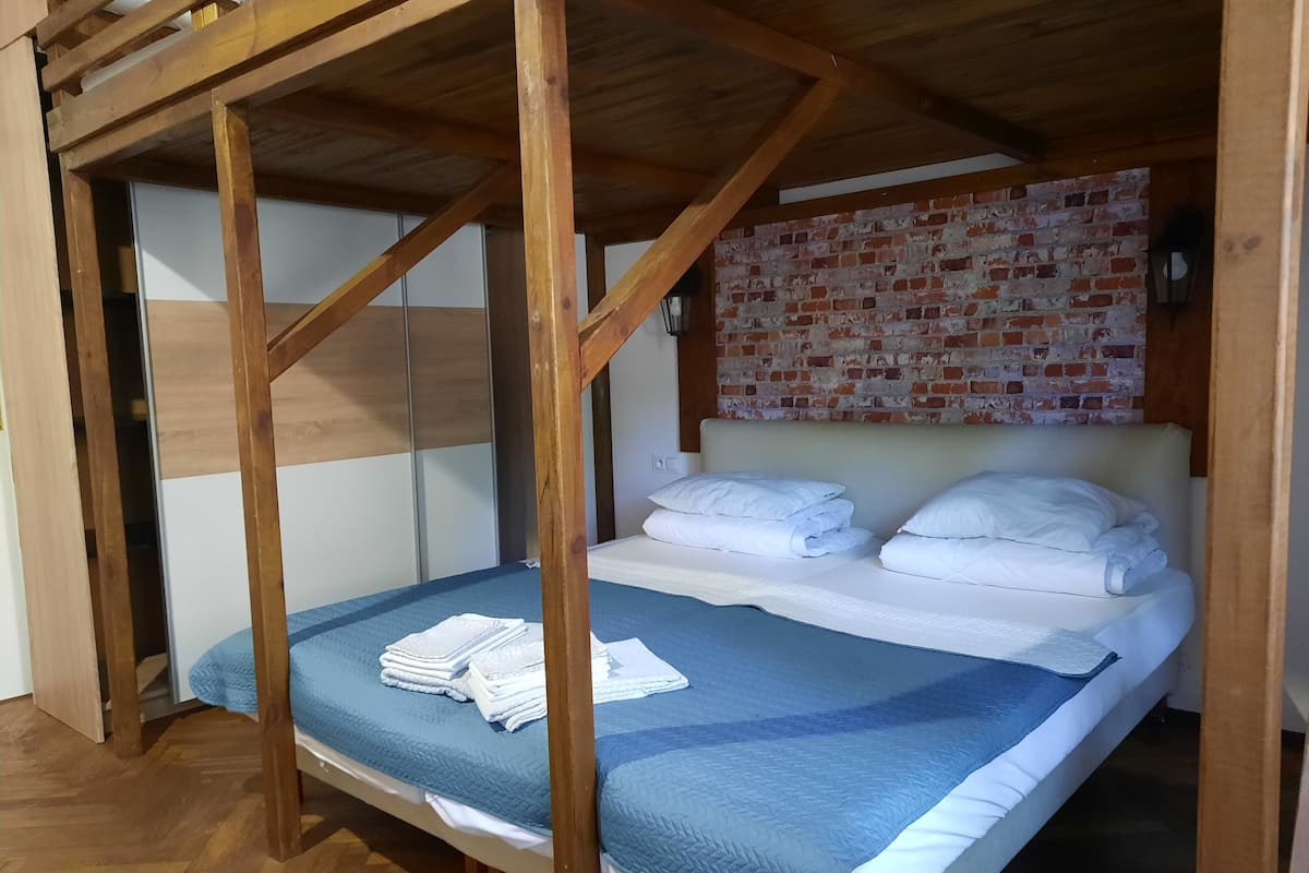 A bunk bed with a wooden frame, a blue quilt, and white pillows.