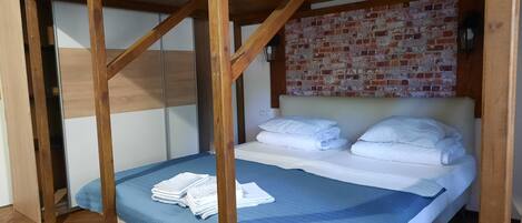 A bunk bed with a wooden frame, a blue quilt, and white pillows.