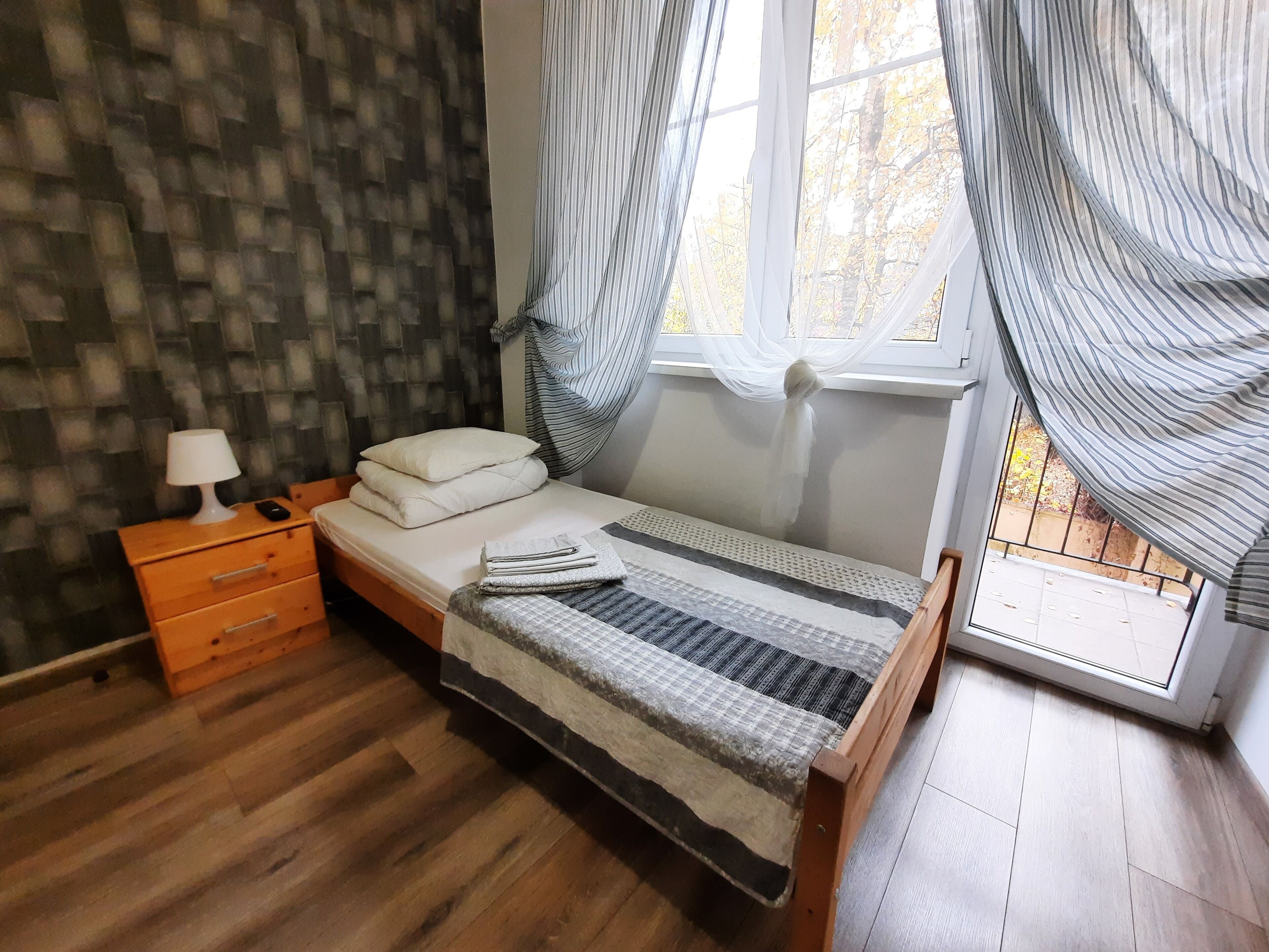 Una camera da letto con un letto di legno, un comodino, una lampada e una finestra con tende.