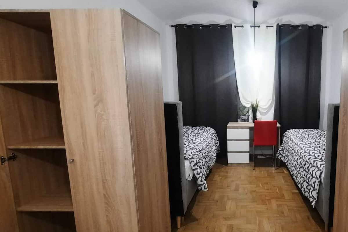 A narrow room with two beds, a desk, and a wardrobe.