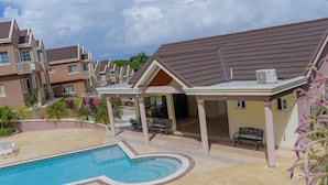 Ein Wohngebäude mit Schwimmbad, Terrassenmöbeln und einer überdachten Sitzgelegenheit im Freien.