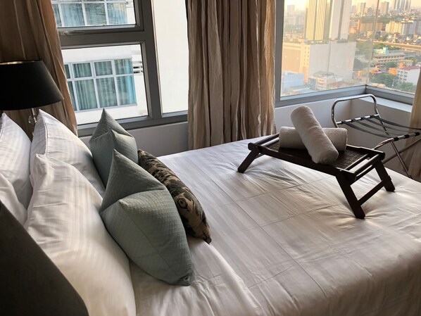 A neatly made bed with pillows and a towel rack with a towel.