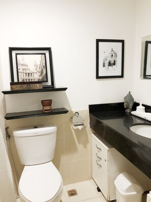 A bathroom with a toilet, a sink, a mirror, and two framed pictures on the wall.