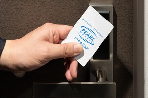 A hand holding a card with "PEARL HOTELS" written on it.