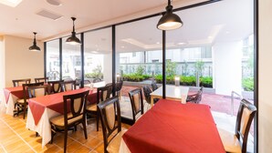 Un restaurante con varias mesas y sillas, amplias ventanas y vistas al exterior.