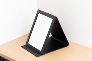 A black, foldable display stand on a wooden surface.