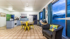 A compact living space with a kitchenette, dining area, and a sofa by a large window.