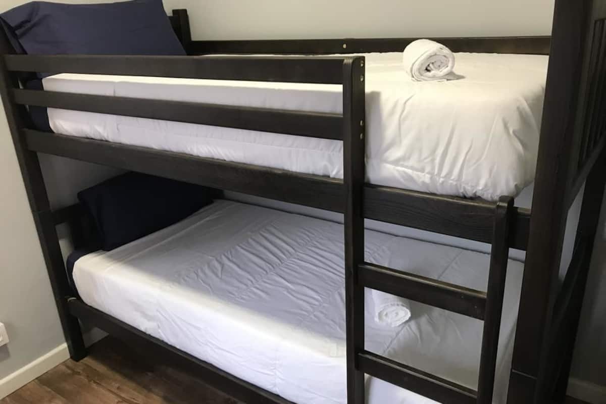 A bunk bed with white bedding and a rolled towel on the top bunk.