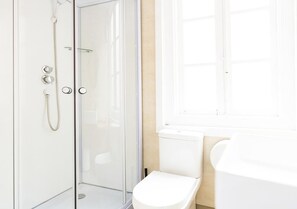 A modern bathroom with a glass-enclosed shower, a white toilet, and a bathtub. - Estrella Suites - Hostel (Vigo)
