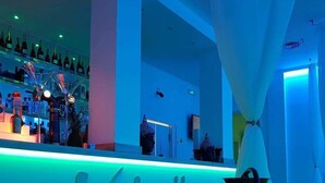 Un coin bar avec un panneau néon indiquant « Valentina's » et une rangée de bouteilles alignées sur des étagères.