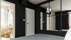 Une chambre à coucher avec un lit, un grand miroir, un téléphone et une porte.