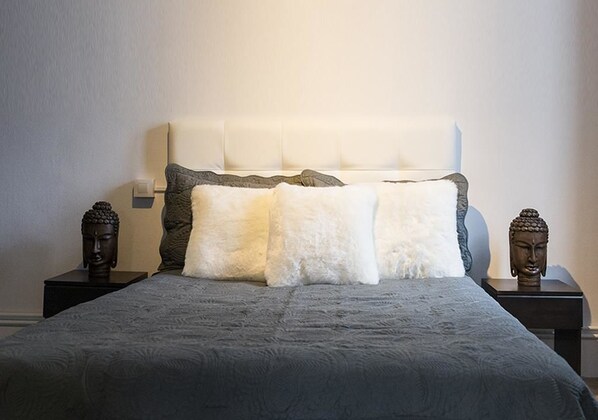 Un dormitorio con una cama, dos mesitas de noche y dos estatuas de Buda.