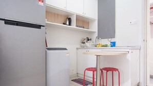 A compact kitchen with a refrigerator, a small sink, and a dining area with two stools. - Centrestage - Heart of Petaling Jaya 1 (Petaling Jaya)