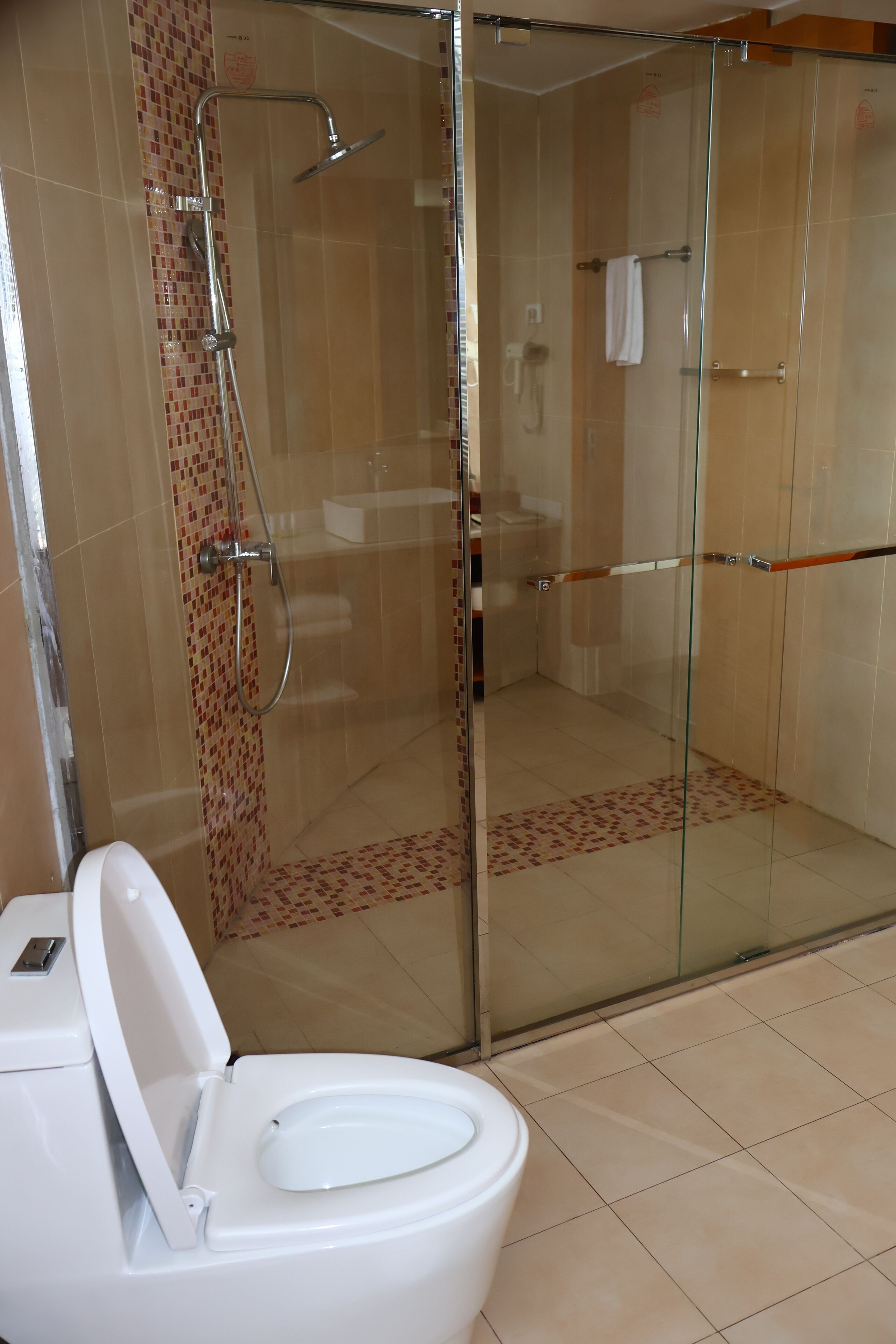 Un baño con ducha acristalada, inodoro blanco y paredes con azulejos.