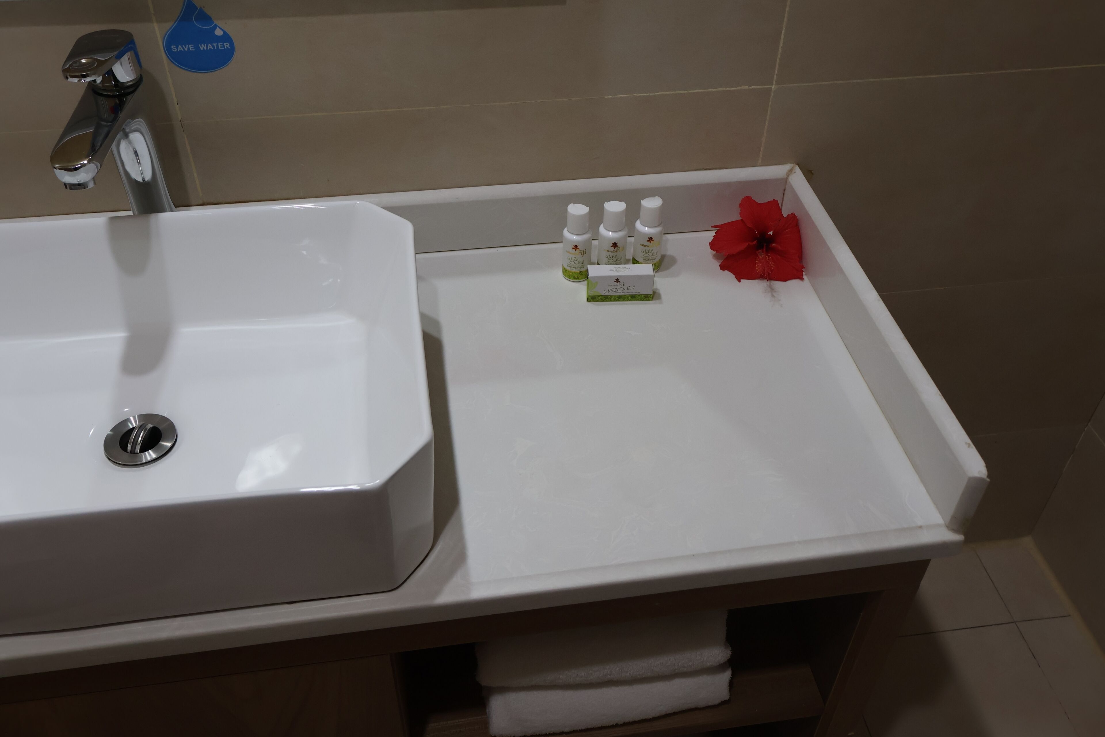 A bathroom with a white sink, a faucet, and a small shelf with toiletries.