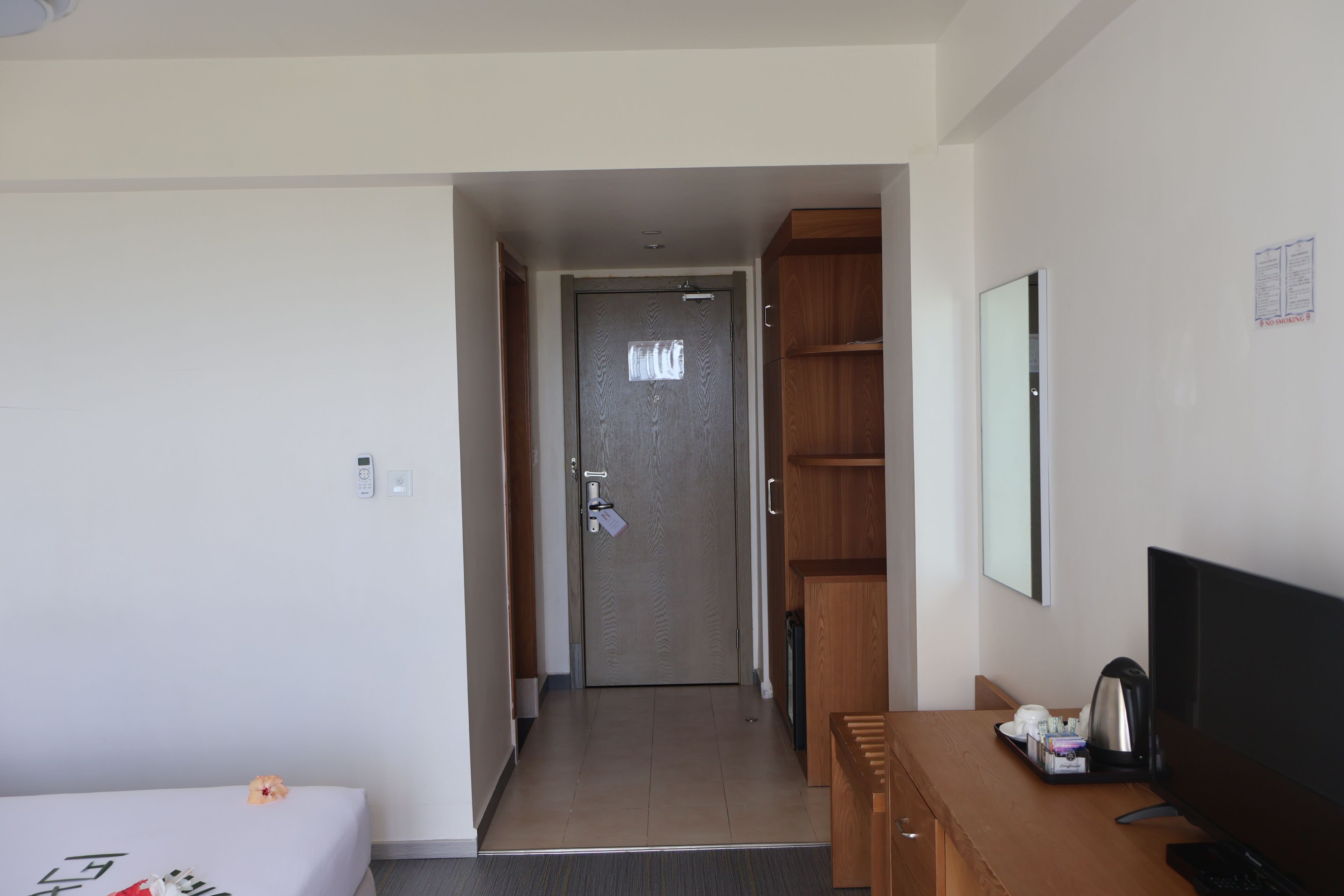 Habitación de hotel con cama, escritorio con computadora, televisor y puerta que da a otra habitación.