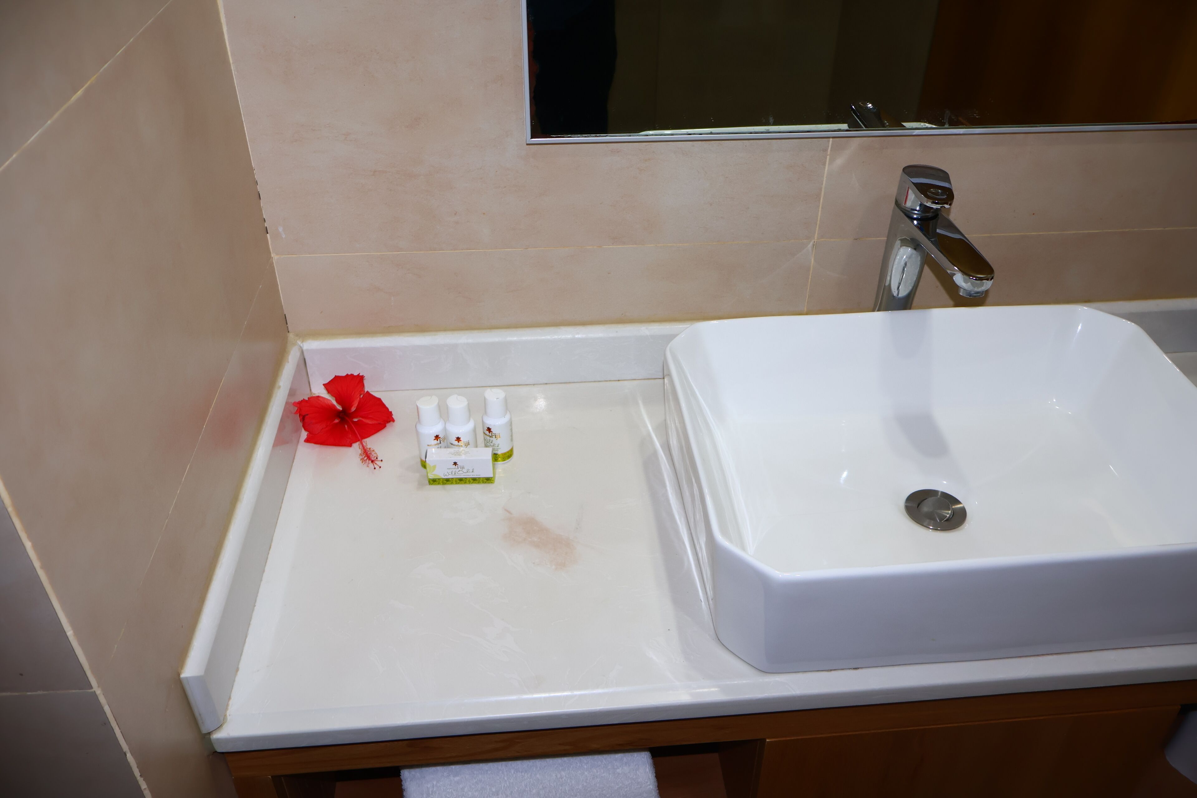 Un baño con un lavabo blanco, un espejo encima y un ventanal pequeño.