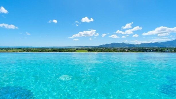 A clear view of a turquoise ocean with a distant shoreline and mountains.