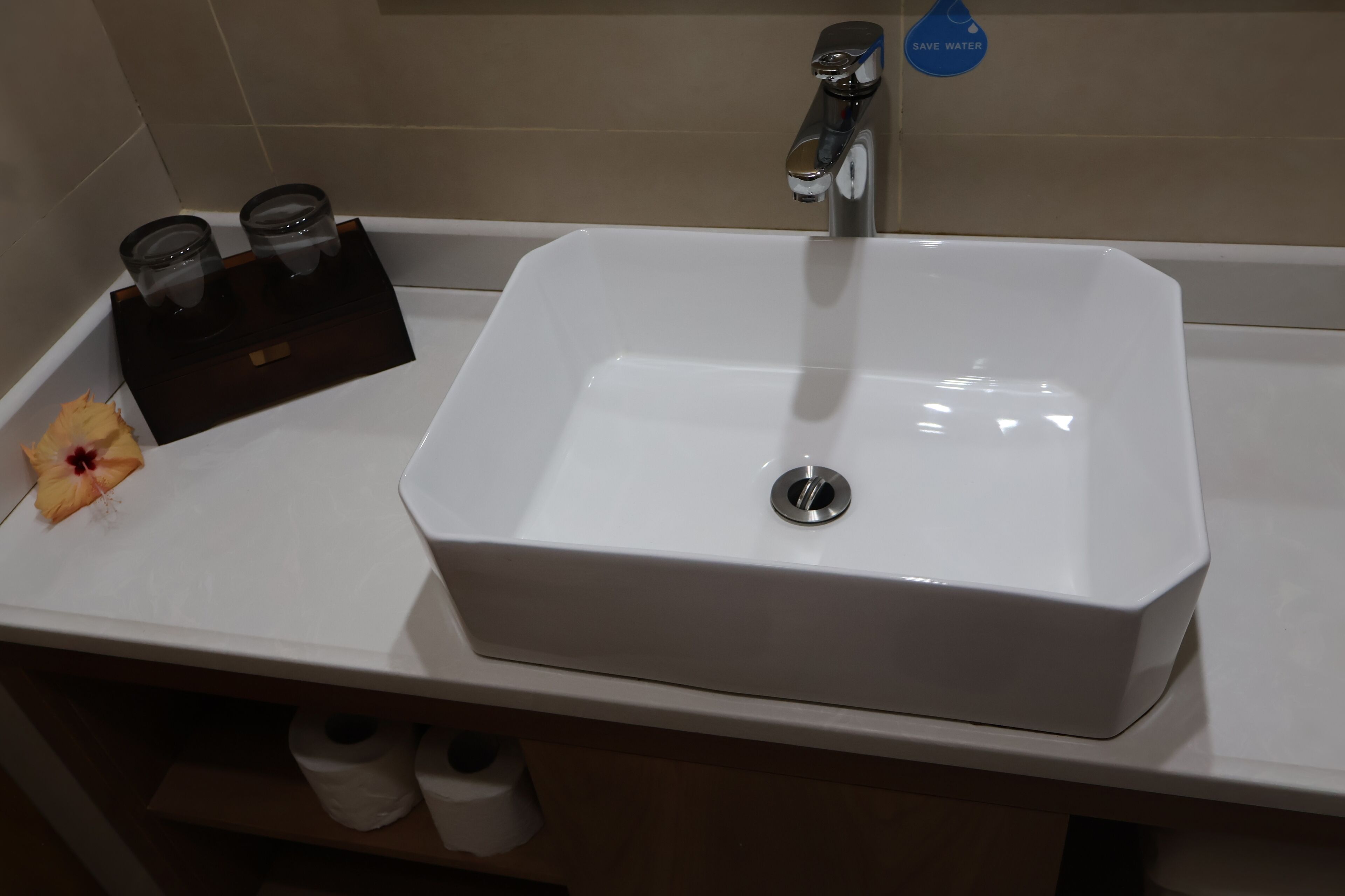 A bathroom sink with a faucet, a tissue holder, and a toilet paper roll.
