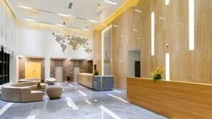 A modern lobby with a reception desk, seating area, and decorative lighting.