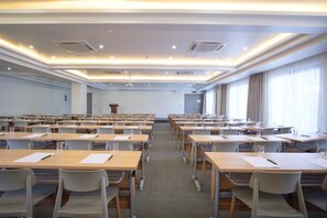 A conference room with rows of tables and chairs, a podium, and large windows with curtains. - Nalagi Hotel (Nadi)