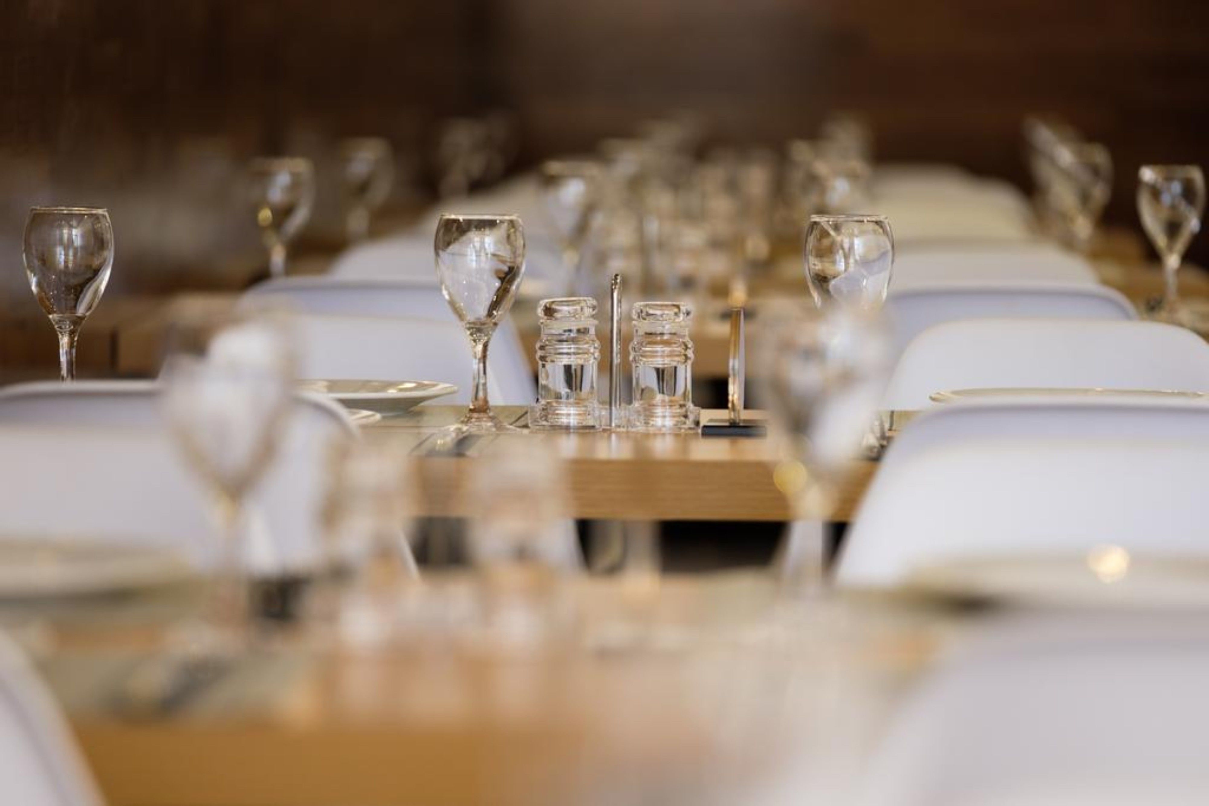 A dining table set with multiple wine glasses and clear glassware, suggesting a formal dining setting.