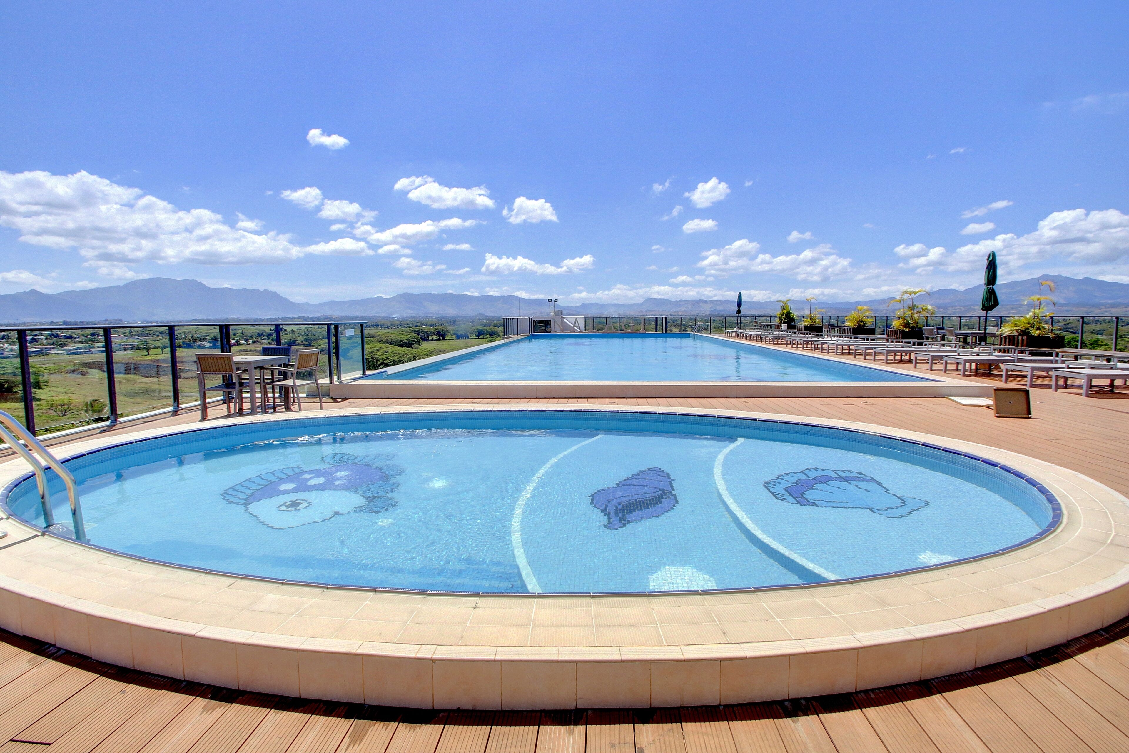 A rooftop swimming pool with a clear view of mountains in the background.