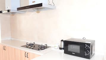 Une cuisine équipée d’une cuisinière à gaz, d’un four à micro-ondes et de meubles de rangement en bois.