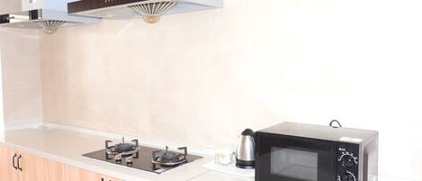 A kitchen with a gas stove, a microwave, and wooden cabinets.