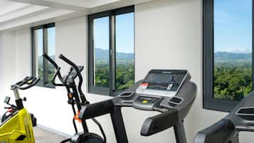A modern gym with exercise equipment and large windows offering a view of a mountainous landscape.