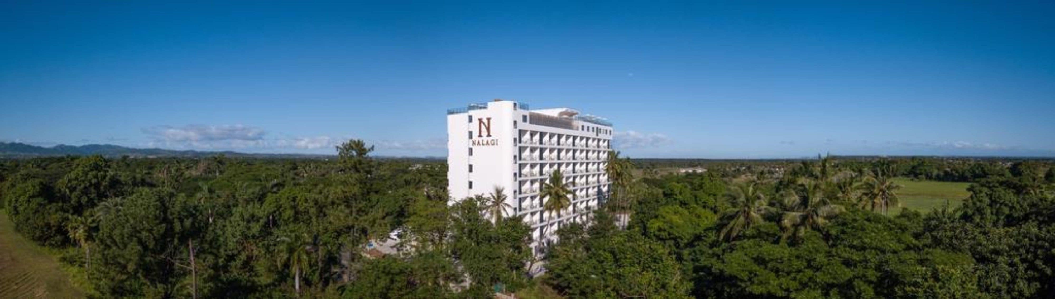 Un hotel dal design moderno, immerso nel verde e con un cielo azzurro intenso.