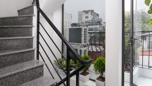 A modern staircase with granite steps and black railings, leading to a balcony with potted plants and a view of buildings. - Hanoi Golden Hotel (Hanoi)
