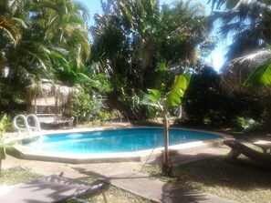 Une piscine entourée d’une végétation luxuriante, notamment de palmiers et de bananiers.