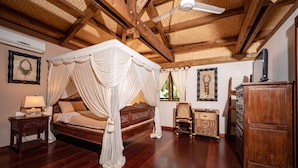 Ein Schlafzimmer mit Himmelbett, Holzmöbeln und Deckenventilator.