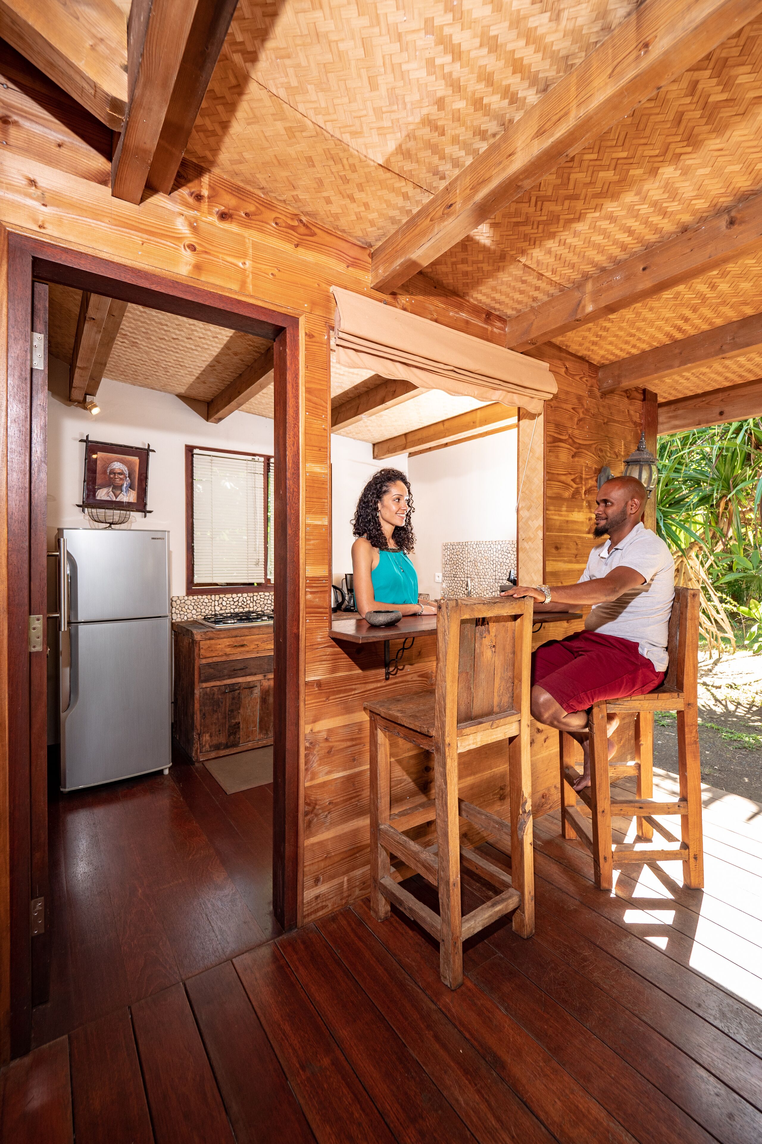 A wooden interior with a kitchen area, a dining table, and a wooden ceiling.