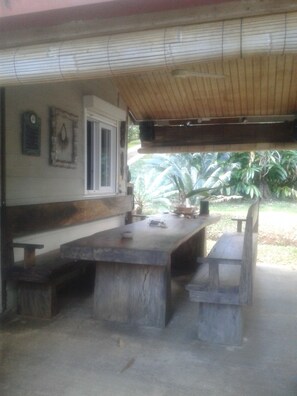 Une terrasse extérieure avec une table et des bancs en bois, une fenêtre et une plaque fixée au mur.