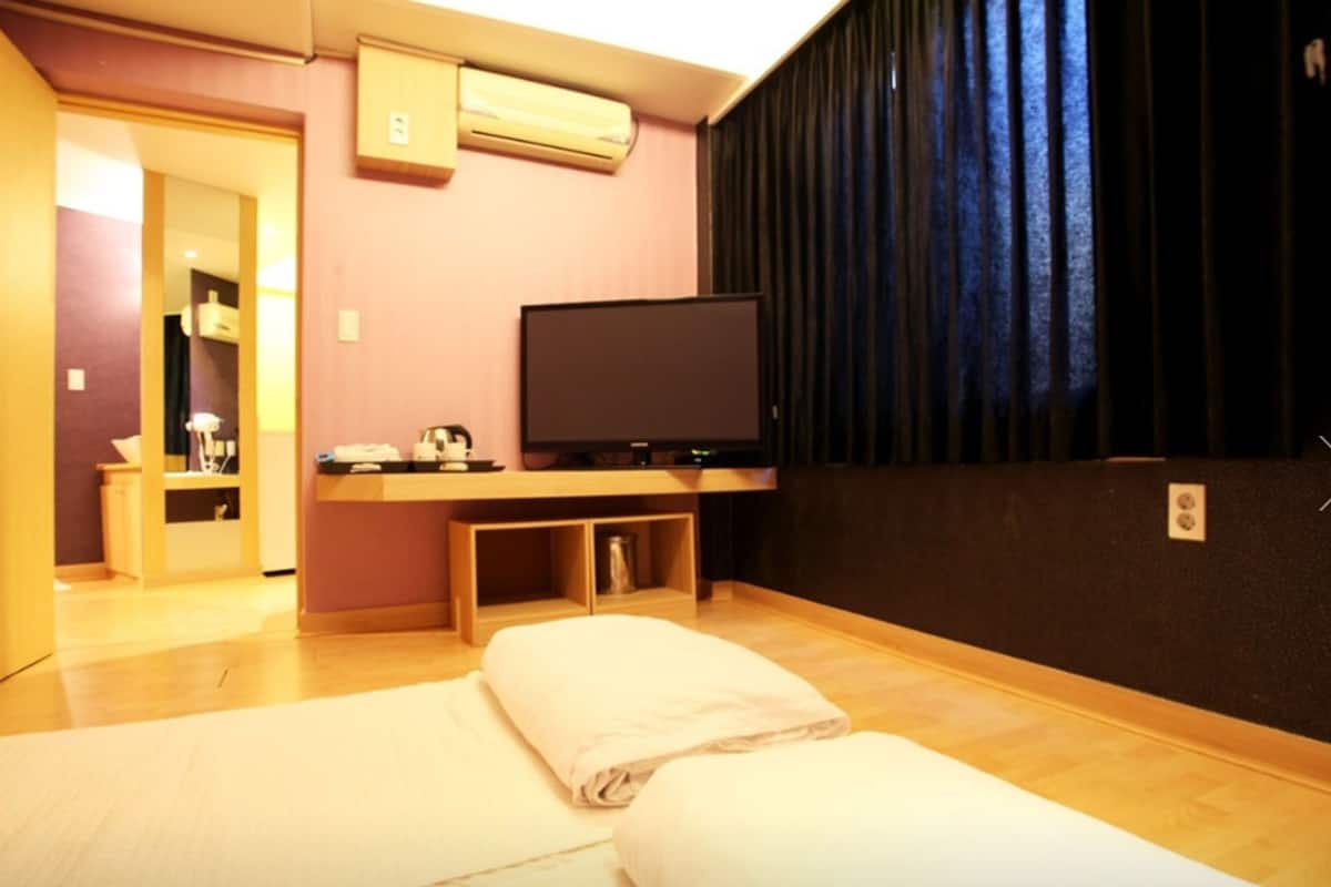 A hotel room with a bed, a television, a small desk, and a wardrobe.