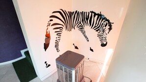 Una habitación con un adhesivo mural de cebra, un calentador y un tapete verde.