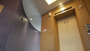 Una puerta de madera con un letrero con la letra 'W', una lámpara en el techo y un respiradero.