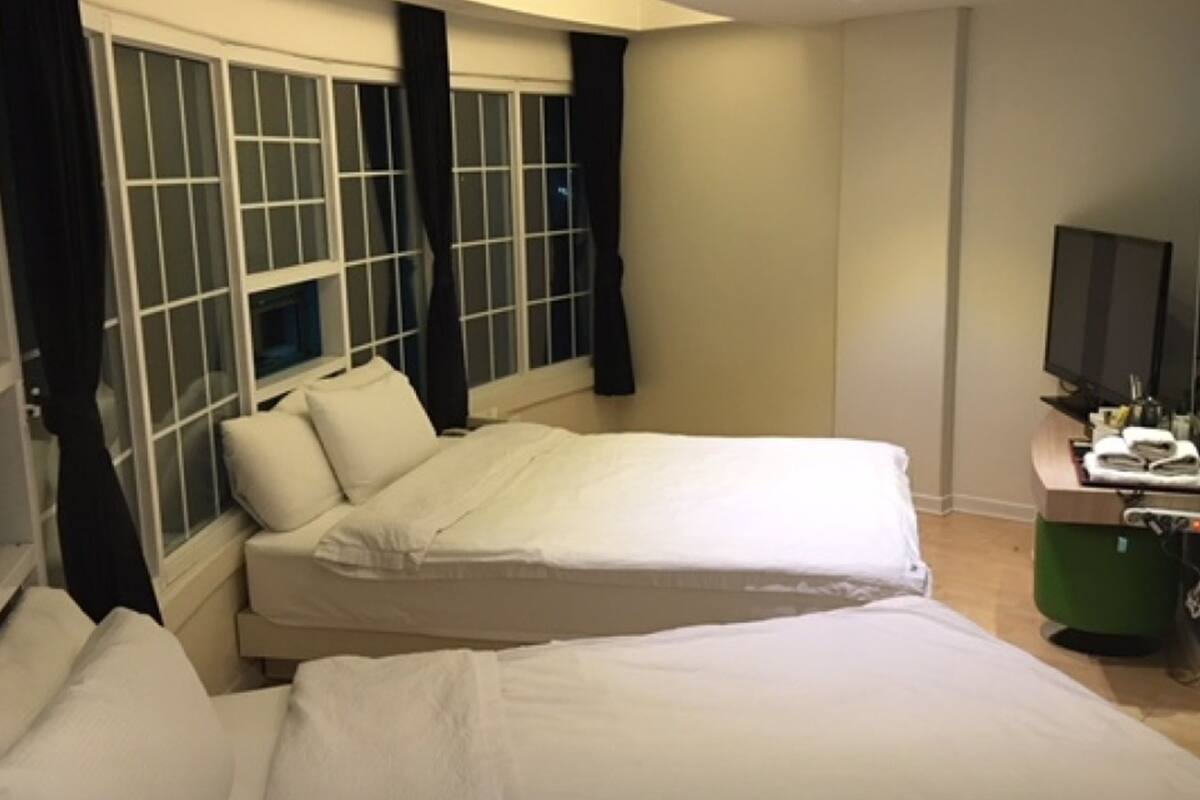 A hotel room with two beds, a television, and a desk with a telephone.